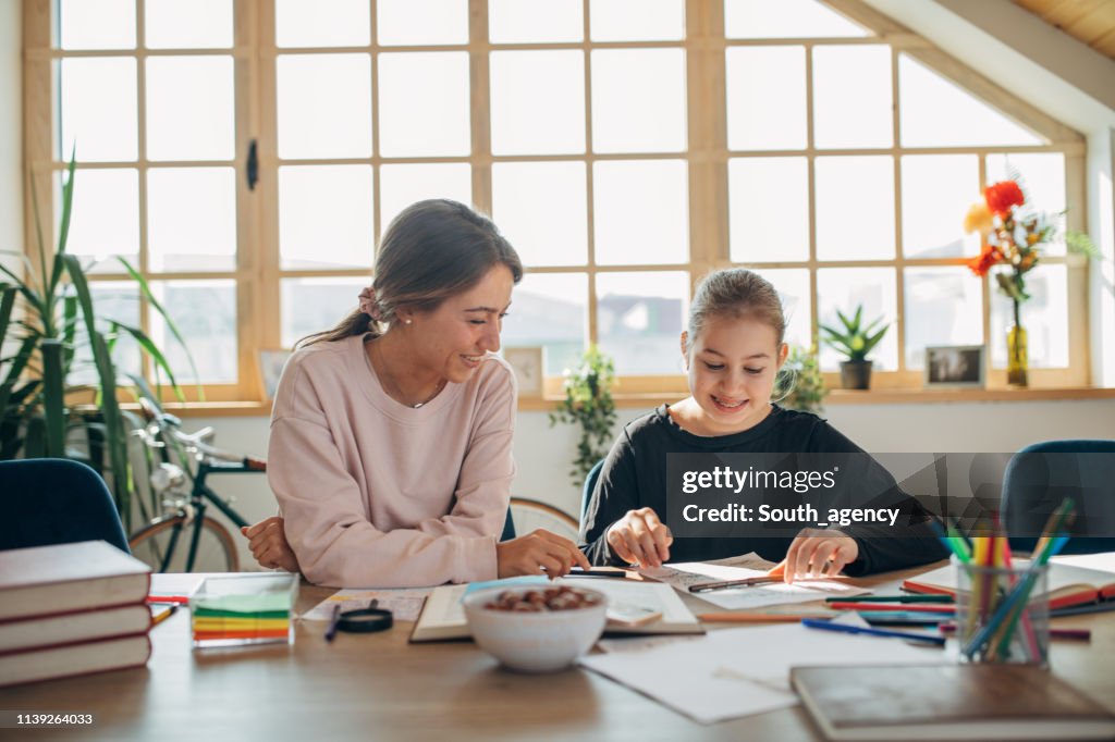 Cute girl on private class with young woman teacher at home
