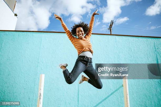 celebrating woman jumps into the air - live celebration stock pictures, royalty-free photos & images