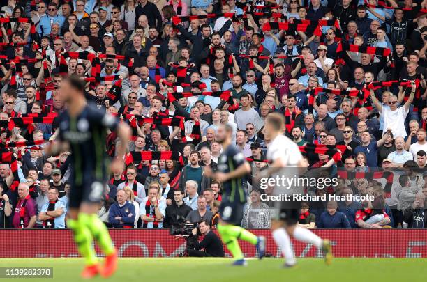 Fans hold up red and black scarves in tribute to Bernard Halford, former club secretary, during the Premier League match between Fulham FC and...