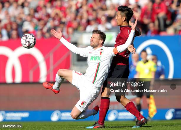 Daniel Baier of Augsburg battles for possession with Yuya Kubo of Nuernberg during the Bundesliga match between 1. FC Nuernberg and FC Augsburg at...
