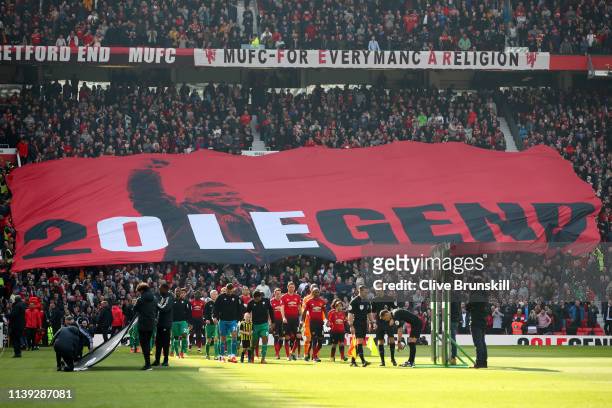 The two teams walk out as the Manchester United fans hold up a banner for Ole Gunnar Solskjaer, Manager of Manchester United prior to the Premier...