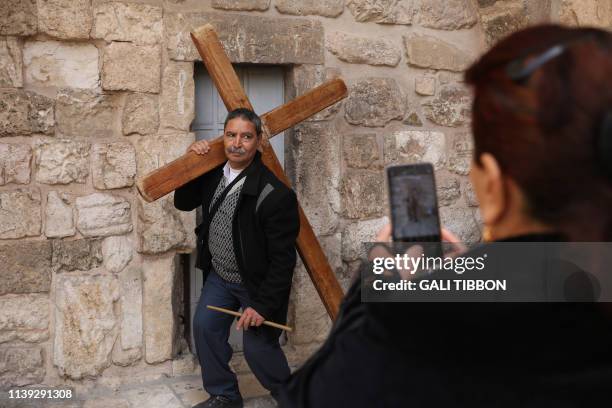 Coptic Orthodox pilgrim poses for a picture as he carries a wooden cross at the church of the Holy Sepulchre in Jerusalem's Old City, on April 25,...