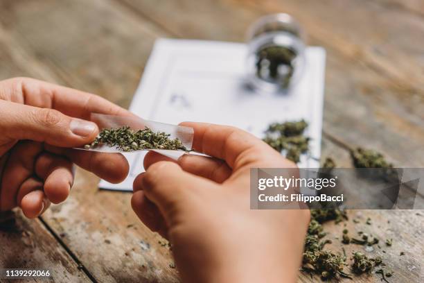 マリファナの関節をローリング若い大人の男 - marijuana   herbal cannabis ストックフォトと画像