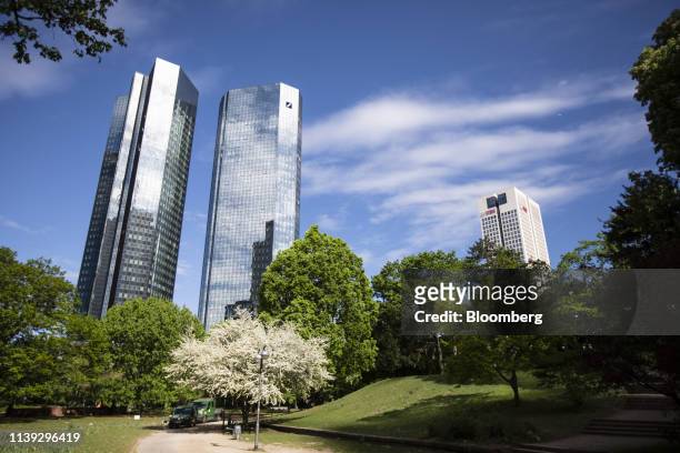 The Deutsche Bank AG twin tower headquarters, left, and the offices of UBS Group AG stand beyond a park in the financial district in Frankfurt,...
