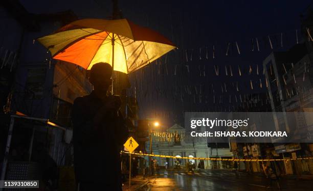 Man walks with an umbrella under the rain near St. Anthony's Shrine in Colombo on April 25 following a series of bomb blasts targeting churches and...