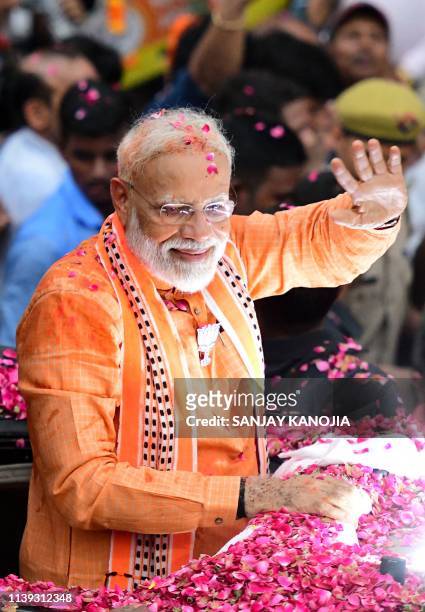 Indian Prime Minister and leader of the Bharatiya Janata Party Narendra Modi waves to political supporters during a roadshow in Varanasi on April 25,...
