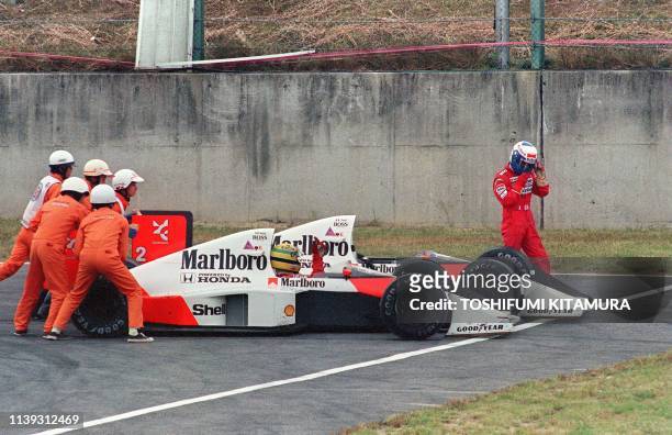 Ayrton Senna of Brazil is given a push from circuit marshals for a restart while his teammate and bitter rival Alain Prost of France leaves his car...