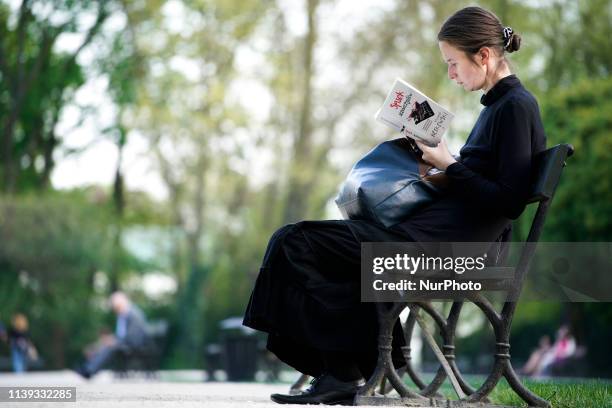 Woman reads a book on a warm Spring day in the Royal Baths Park in Warsaw, Poland on April 25, 2019.