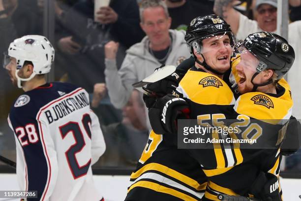 Oliver Bjorkstrand of the Columbus Blue Jackets looks on as Noel Acciari celebrates with Joakim Nordstrom of the Boston Bruins after scoring in the...