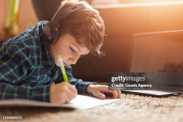 teenage boy listening to music while doing homework - boy headphones imagens e fotografias de stock