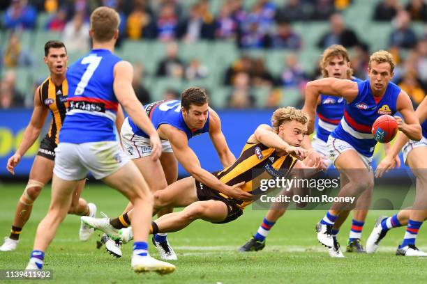 James Worpel of the Hawks handballs whilst being tackled by Josh Dunkley of the Bulldogs during the round two AFL match between the Hawthorn hawks...