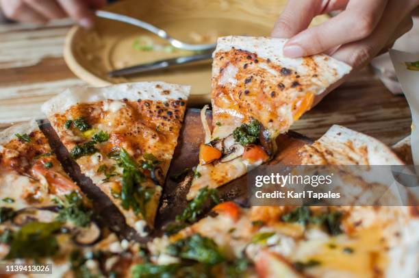 a young woman is eating a freshly made pesto mushroom pizzadilla - tortilla stock pictures, royalty-free photos & images