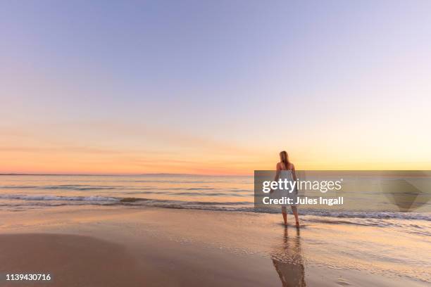 sole woman on the beach at sunset in a white dress - noosa heads stock pictures, royalty-free photos & images