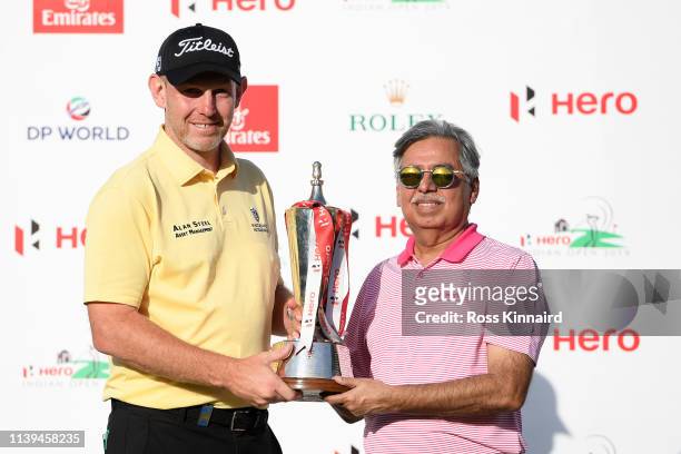 Stephen Gallacher of Scotland poses with the trophy and Pawan Munjal of HERO during the final round on day four of the Hero Indian Open at the DLF...