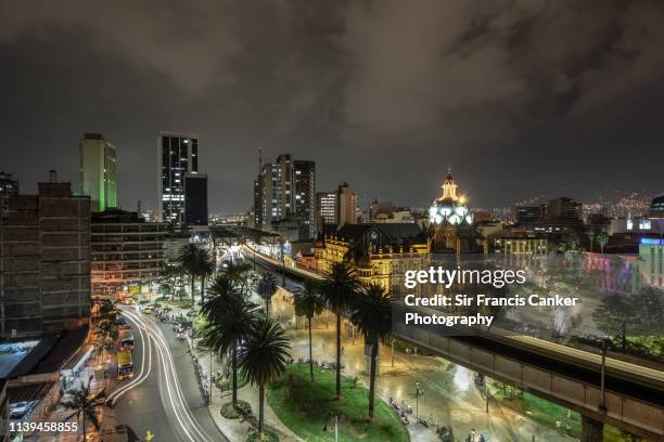 medellin skyline illuminated at night with blurred lights of elevated metro and traffic lights in antioquia, colombia - medellin colombia stock pictures, royalty-free photos & images