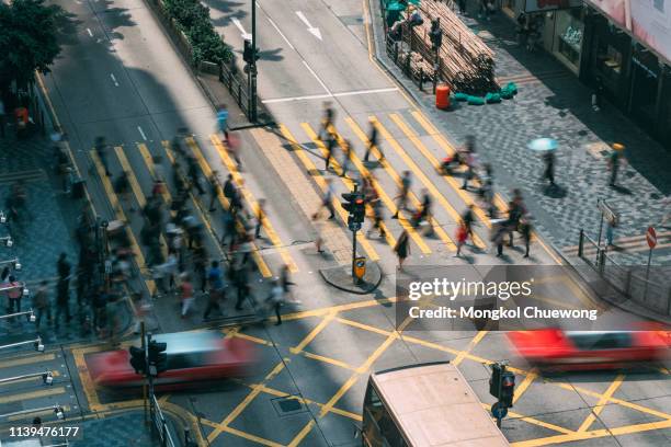 people and taxi cabs crossing a very busy crossroads in tsim sha tsui district hong kong, china - hong kong fotografías e imágenes de stock