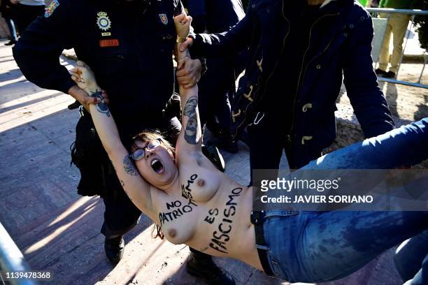 Spanish police carry an activist from the women's rights organisation Femen as they disperse a protest before the start of Spanish far-right party...