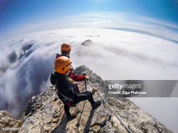 couple of climbers following via ferrata into a foggy valley - slovenia austria stock pictures, royalty-free photos & images