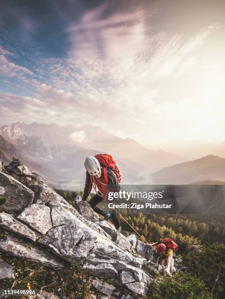 un par de alpinistas, subiendo a través de ferrata, una ruta de escalada segura - alpinismo fotografías e imágenes de stock