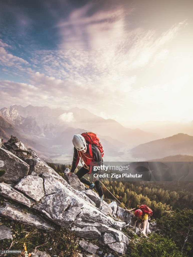 Couple of mountain climbers, climbing via ferrata, a secure climbing route