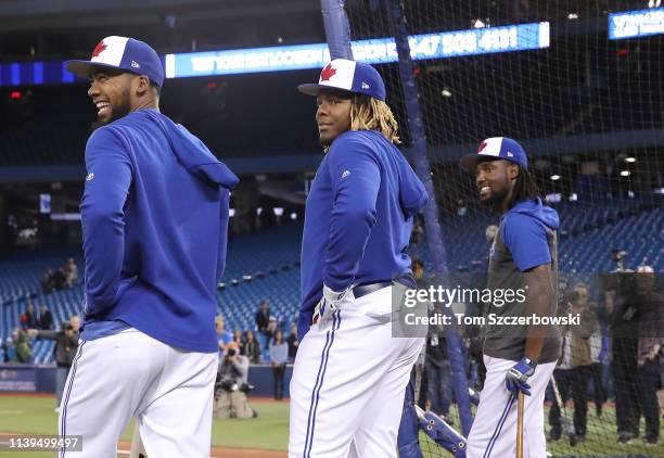 Vladimir Guerrero Jr. #27 of the Toronto Blue Jays and Teoscar Hernandez and Alen Hanson smile as they look on during batting practice before the...
