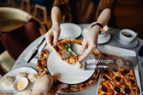 close up of couple enjoying meal and sharing pizza in a restaurant - hot big women stock pictures, royalty-free photos & images