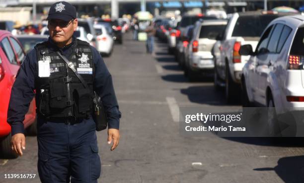 Mexican Federal Police officer keeps watch as cars line up to cross into the United States at the San Ysidro Port of Entry, one of the busiest land...
