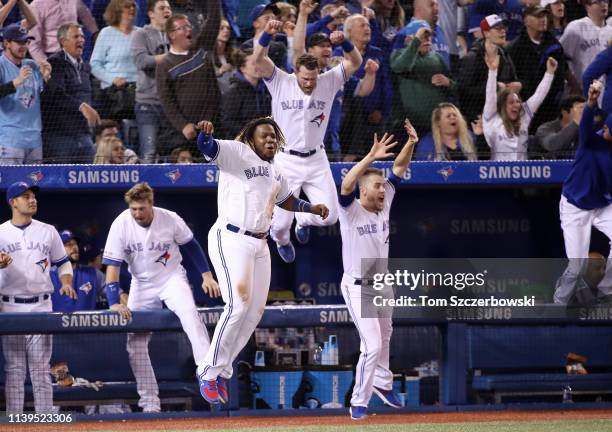 Vladimir Guerrero Jr. #27 of the Toronto Blue Jays celebrates their victory with Billy McKinney and Ken Giles as Brandon Drury hit a game-winning...