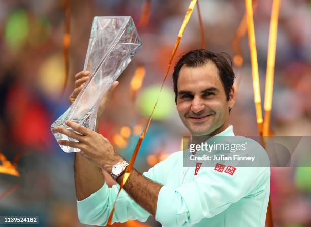 Roger Federer of Switzerland in celebrates with the winners trophy against John Isner of USA in the final during day fourteen of the Miami Open...