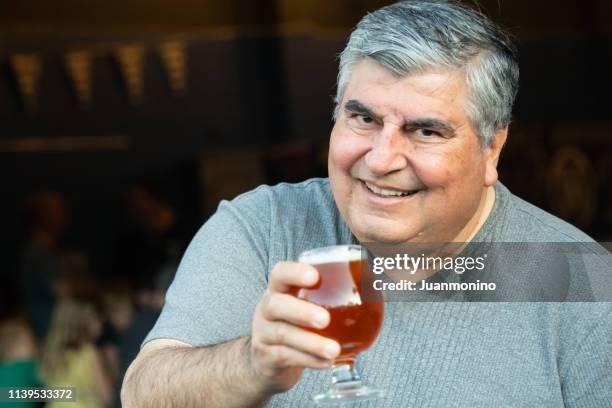 glimlachend overgewicht senior/mature man met een glas bier - man sipping beer smiling stockfoto's en -beelden