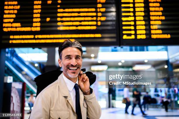 smiling businessman at the train station. - returning computer stock pictures, royalty-free photos & images