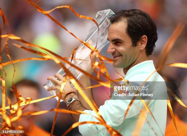 Roger Federer of Switzerland celebrates with the winners trophy against John Isner of USA in the final during day fourteen of the Miami Open tennis...