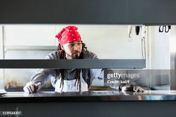 mixed race man with dreadlocks in commercial kitchen - view-through-restaurant-window stock pictures, royalty-free photos & images