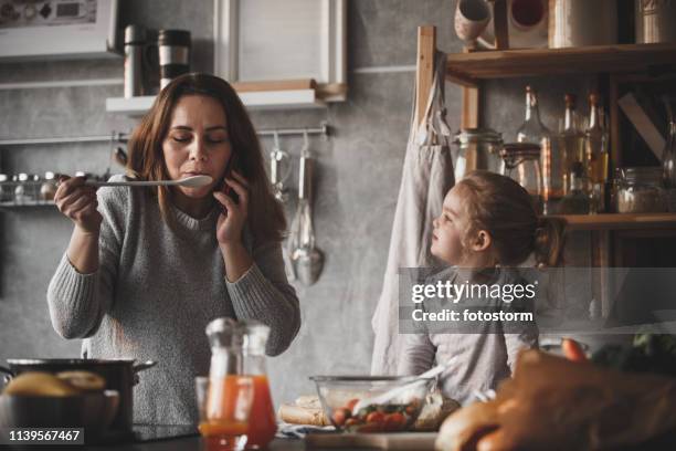 madre al teléfono, cocinando - sabor fotografías e imágenes de stock