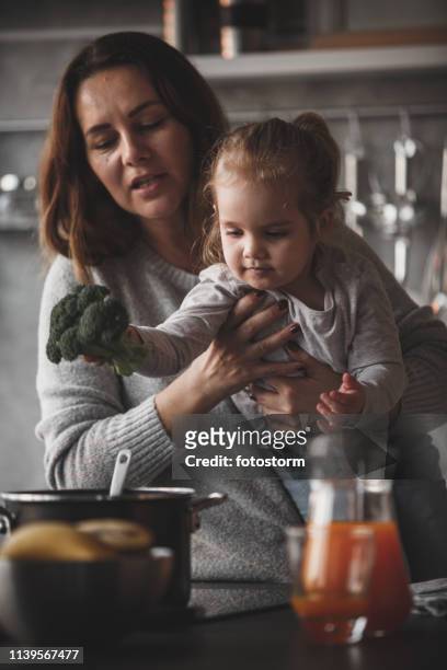 little girl puts broccoli in the cooking pan - kid stock stock pictures, royalty-free photos & images