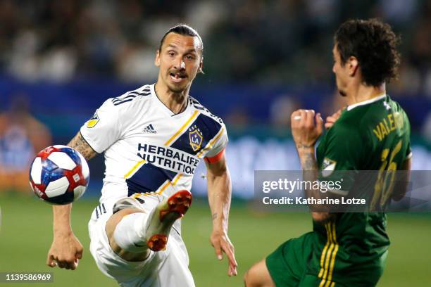 Zlatan Ibrahimovic of Los Angeles Galaxy kicks the ball away from Zarek Valentin of Portland Timbers during the second half at Dignity Health Sports...