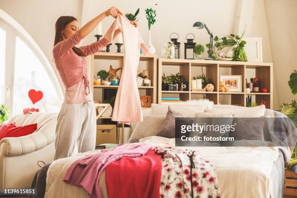 mujer preparando vestimenta diaria en el dormitorio - folding fotografías e imágenes de stock