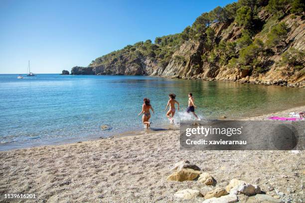 amis éclaboussant l’eau tout en exécutant sur le rivage - province-de-barcelone photos et images de collection