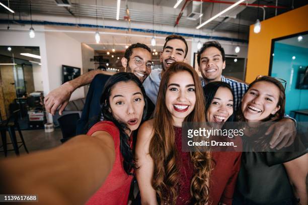 colleagues taking selfie after project conference in company with hispanic employees - office fun stock pictures, royalty-free photos & images