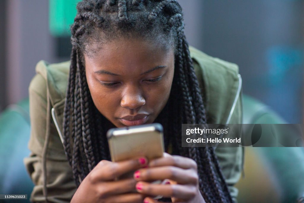 Young woman intently reading cell phone