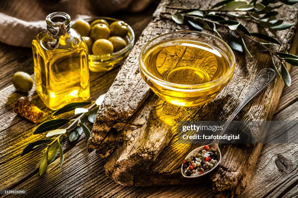 Aceite de oliva y aceitunas verdes filmada en mesa rústica de madera