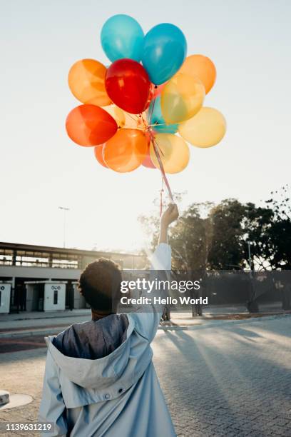 rear view of celebrating person holding balloon up to sun's rays - releasing balloons stock pictures, royalty-free photos & images