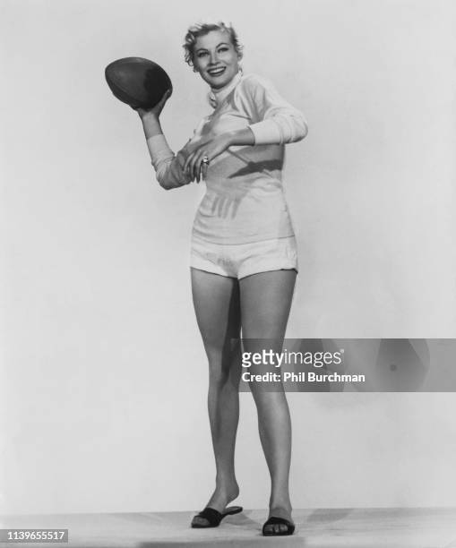 Swedish-born Italian actress Anita Ekberg throwing a football, circa 1955.