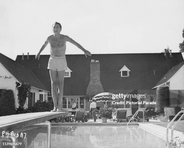 Austrian-born American actor Paul Henreid looks nervous as he prepares to do a backward dive from a diving board, circa 1950.