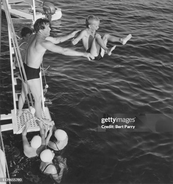American actor and singer Roy Rogers playing with his children on a boat, circa 1955.