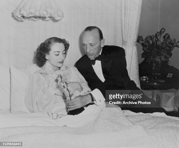 American actress Joan Crawford accepts her Academy Award for Best Actress for the film 'Mildred Pierce' from the film's director Michael Curtiz,...
