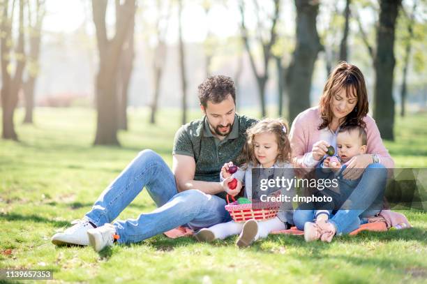 family celebrating easter in the park - easter egg hunt outside stock pictures, royalty-free photos & images