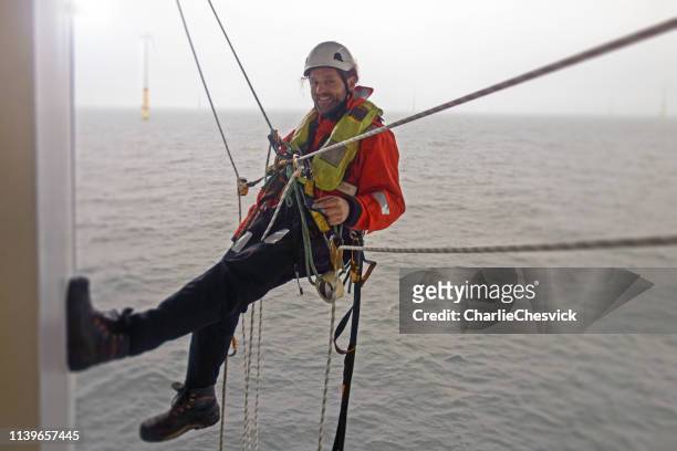 lächelnd manueller highworker offshore-rappel auf offshore-plattform mit ropers - windpark offshore stock-fotos und bilder