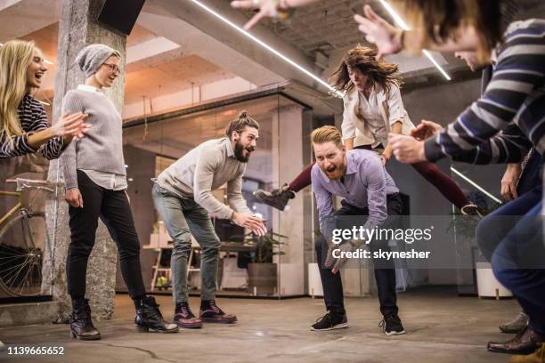 team von spielenden unternehmern, die spaß an einer pause im büro haben. - bockspringen stock-fotos und bilder