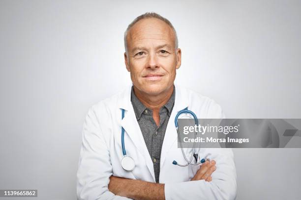 senior male doctor smiling on white background - médecin content photos et images de collection